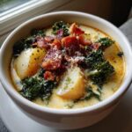 A close-up of a bowl of creamy Zuppa Toscana soup topped with crispy bacon, kale, and grated Parmesan cheese.