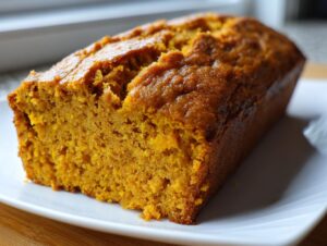 Close-up of a freshly baked, moist loaf of easy pumpkin bread with a cracked, golden-brown top.