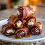 A stack of crispy bacon wrapped stuffed dates filled with white cheese, drizzled with honey.