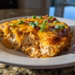 A close-up of a hearty serving of baked texas trash dip, showing a creamy interior topped with melted cheddar and green onions.