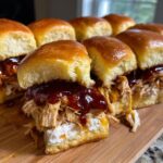 Close-up of several gooey bbq chicken sliders with shredded chicken, cream cheese, and rich BBQ sauce on brioche buns.
