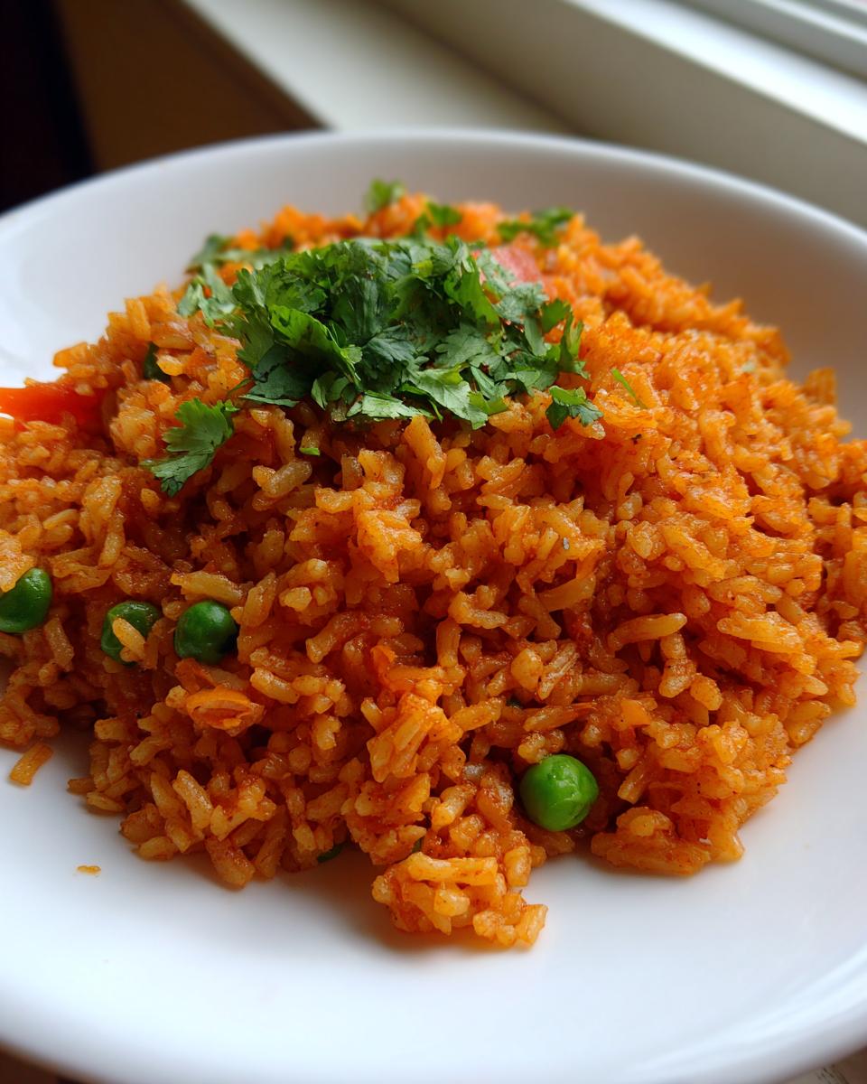 A close-up of fluffy, orange-colored spanish rice topped with fresh cilantro and mixed with green peas.
