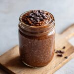 Close-up of rich chocolate overnight oats in a glass jar, topped generously with dark chocolate chips.