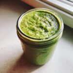 Close-up of thick, bright green matcha chia pudding topped with whole chia seeds in a glass jar.