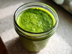 Close-up of vibrant green matcha chia pudding speckled with dark chia seeds, served in a small glass jar.